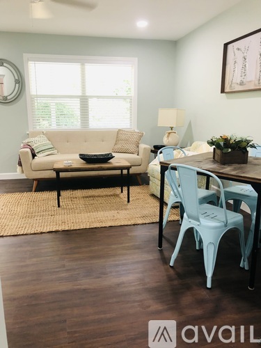 A living room with a beige couch, a coffee table, and a dining table with chairs.