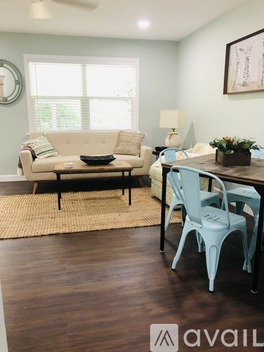 A living room with a beige couch, a coffee table, and a dining table with chairs.