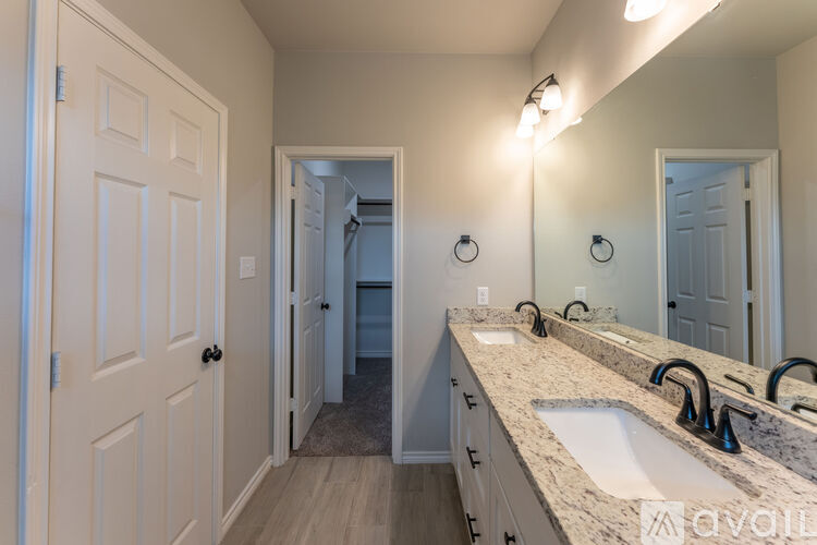 A bathroom with a vanity, sink, mirror, and lighting fixtures.