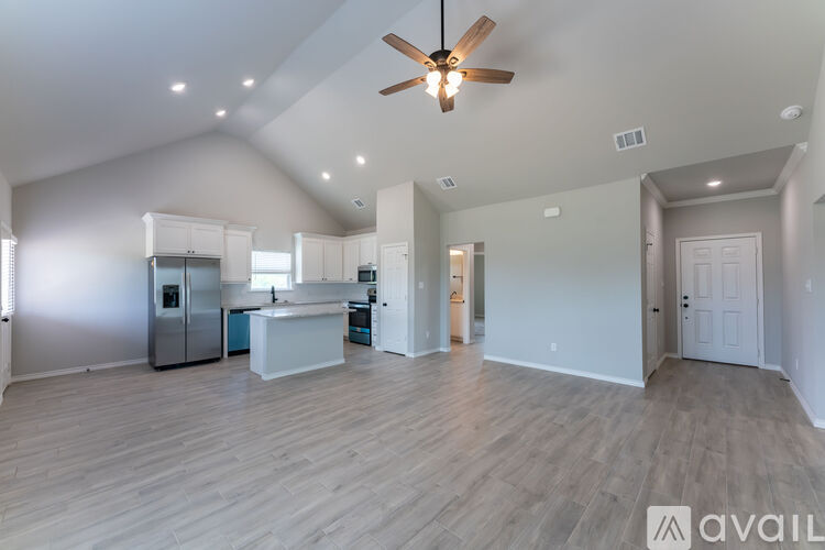A spacious living room with a ceiling fan and lighting fixtures.