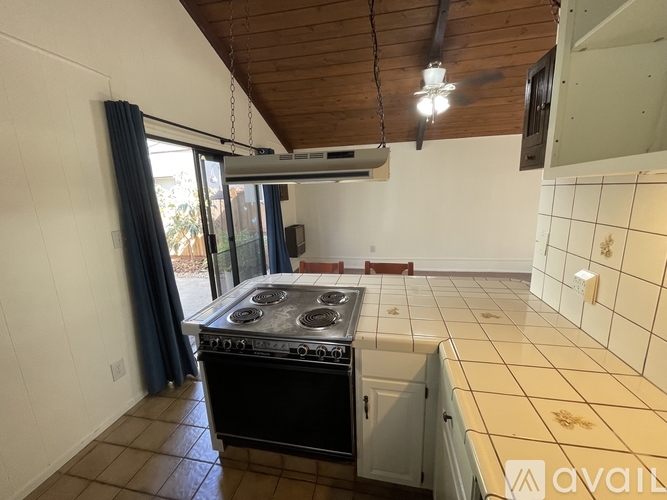 A kitchen with a black stove top oven and a tiled floor.