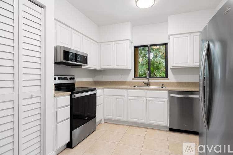 A kitchen with white cabinets and a stainless steel refrigerator.
