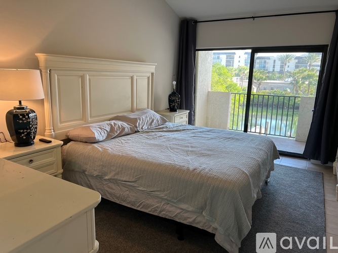 A bedroom with a large bed and a balcony overlooking a pool.