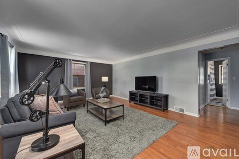 A living room with a grey sofa, a black coffee table, and a wooden floor.