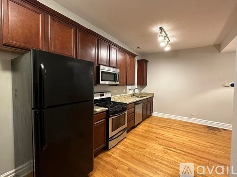 A kitchen with wooden cabinets and a black refrigerator.