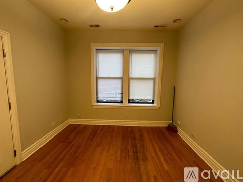 A room with wooden floors and a window with blinds.