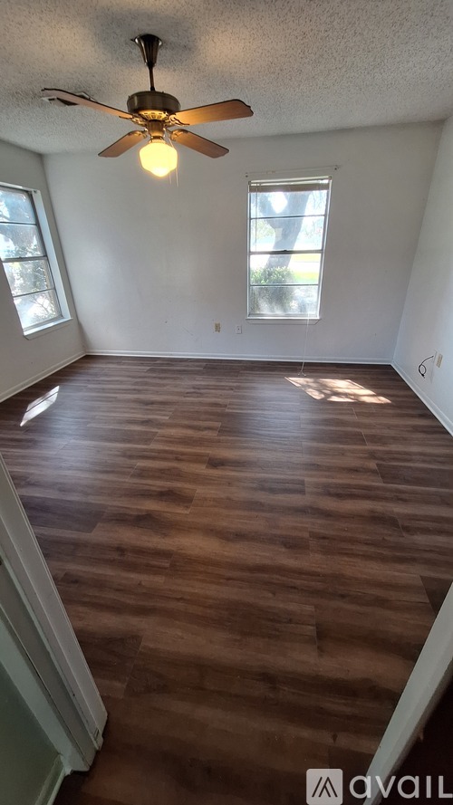 A room with a ceiling fan and wooden flooring.
