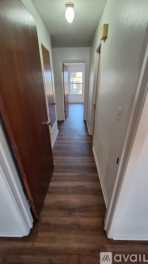 A long hallway with a light on the ceiling and a door at the end.