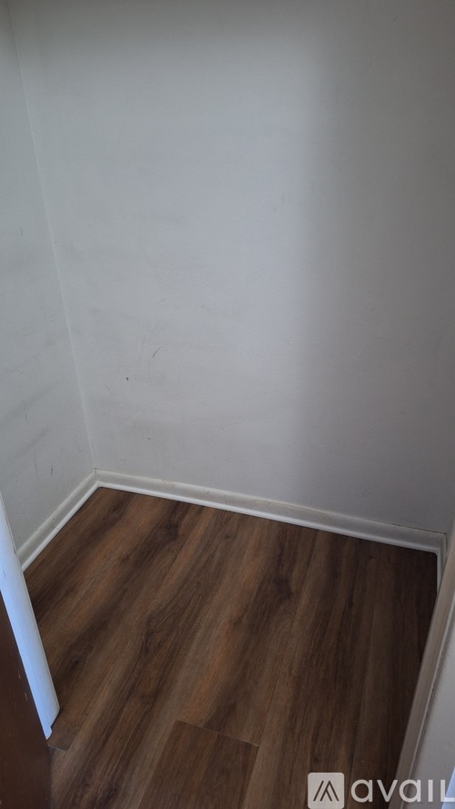 A room with wooden flooring and white walls.