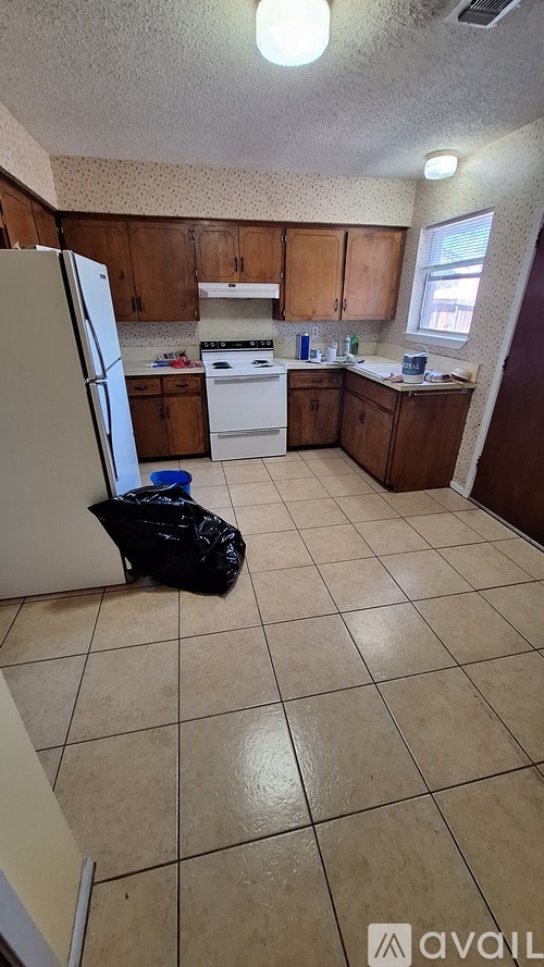 A kitchen with a refrigerator, stove, and cabinets.