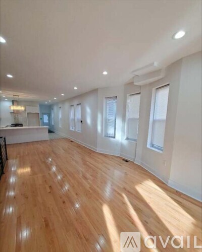 A spacious room with wooden flooring and white walls.