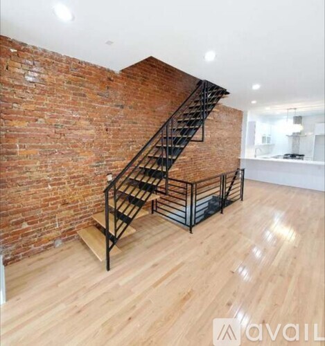 A wooden staircase with metal railings leads up to a brick wall.