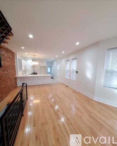 A spacious room with wooden flooring and a brick wall.