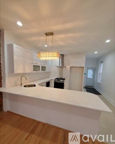 A modern kitchen with white cabinets and a wooden floor.