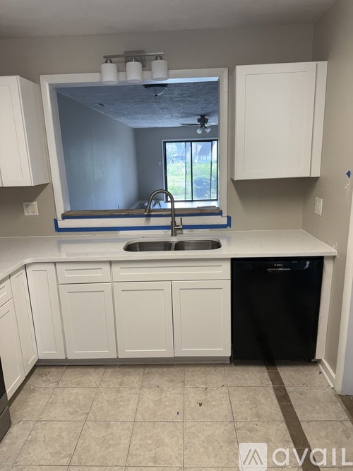 A kitchen with white cabinets and a black dishwasher.