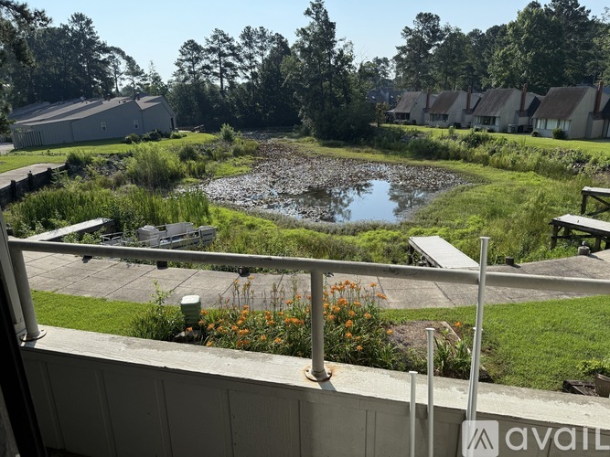 A view from a balcony overlooking a pond and a grassy area with a sign that says "available".