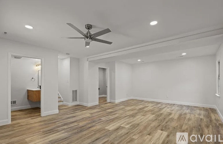 A spacious room with a ceiling fan and wooden flooring.