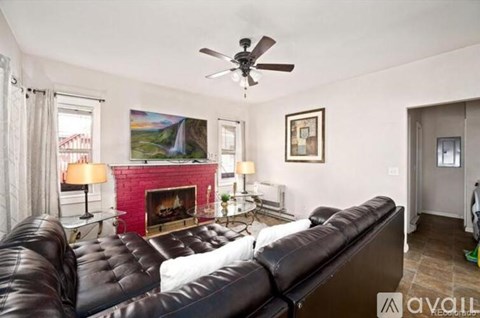 A living room with a black leather couch and a fireplace.