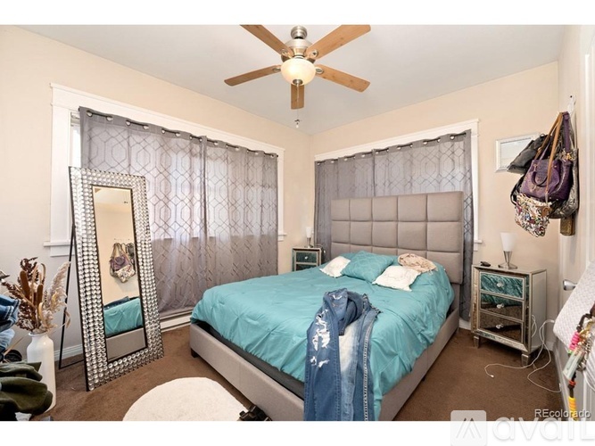 A bedroom with a bed, mirror, and ceiling fan.