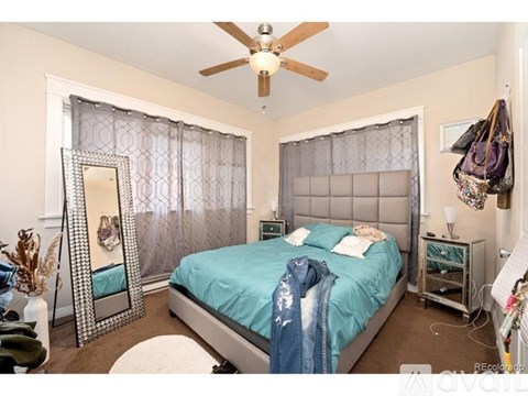 A bedroom with a bed, mirror, and ceiling fan.