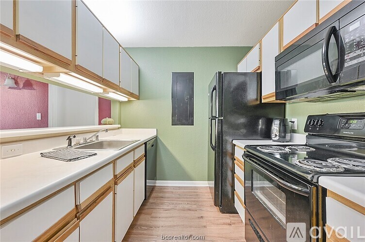 A kitchen with a black refrigerator, black microwave, and black oven.