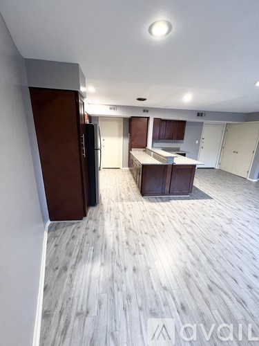 A spacious room with wooden flooring and a kitchen area.