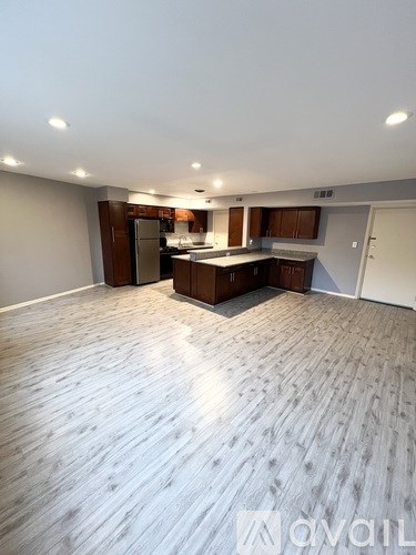 A spacious kitchen with wooden flooring and modern appliances.
