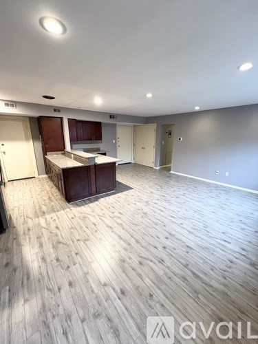 A spacious room with wooden flooring and a kitchen area.