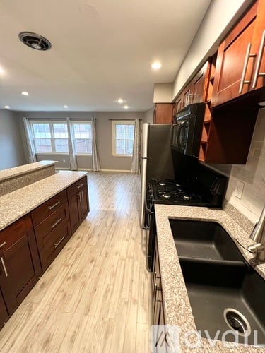 A kitchen with wooden cabinets and a black refrigerator.