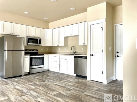 A kitchen with white cabinets and a wooden floor.