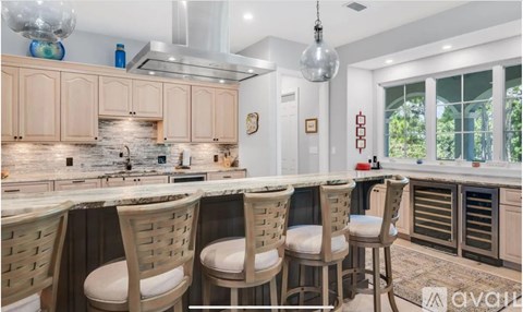 A kitchen with wooden chairs and a marble countertop.