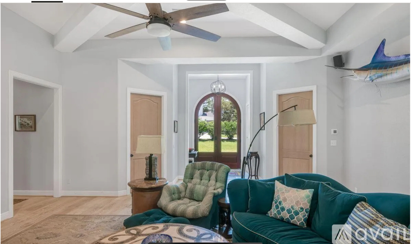 A living room with a green couch and a ceiling fan.