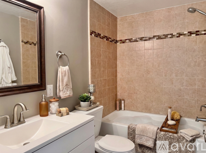 A modern bathroom with a white sink, a white toilet, and a bathtub with a shower head.