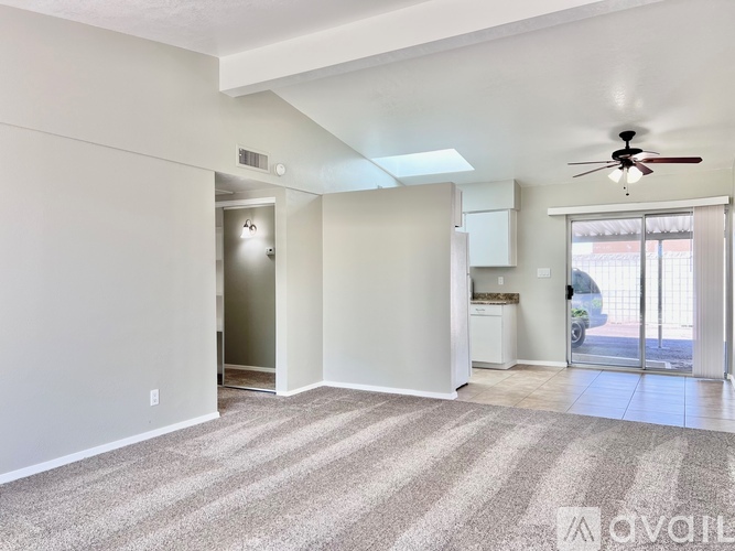 A spacious room with a ceiling fan and striped carpeting.