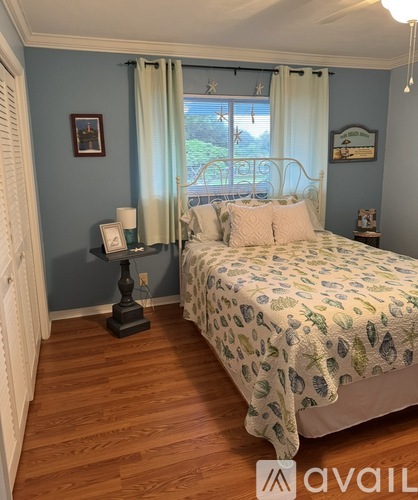 A bedroom with a bed, nightstand, and window with curtains.