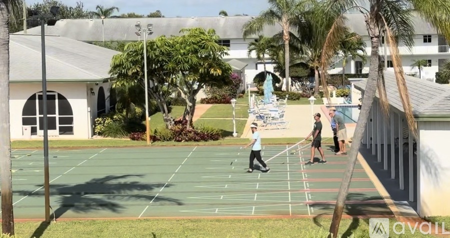 A tennis court with people playing tennis and a building in the background.