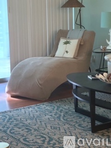 A living room with a chair covered in a beige blanket and a small table with a lamp.