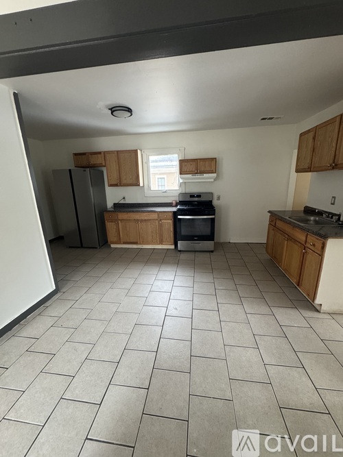A kitchen with tile flooring and wooden cabinets.