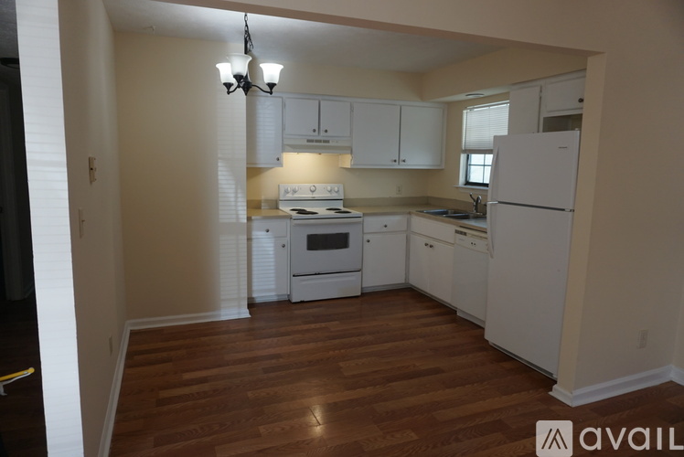 A kitchen with white appliances and wooden floors.