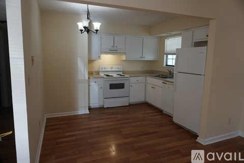 A kitchen with white appliances and wooden floors.