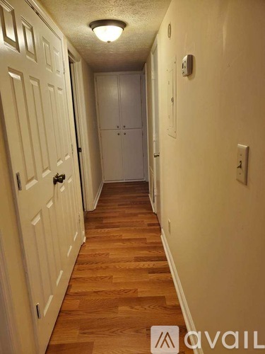 A hallway with wood floors and white walls.