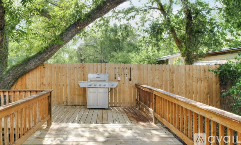 A wooden deck with a grill and a fence.