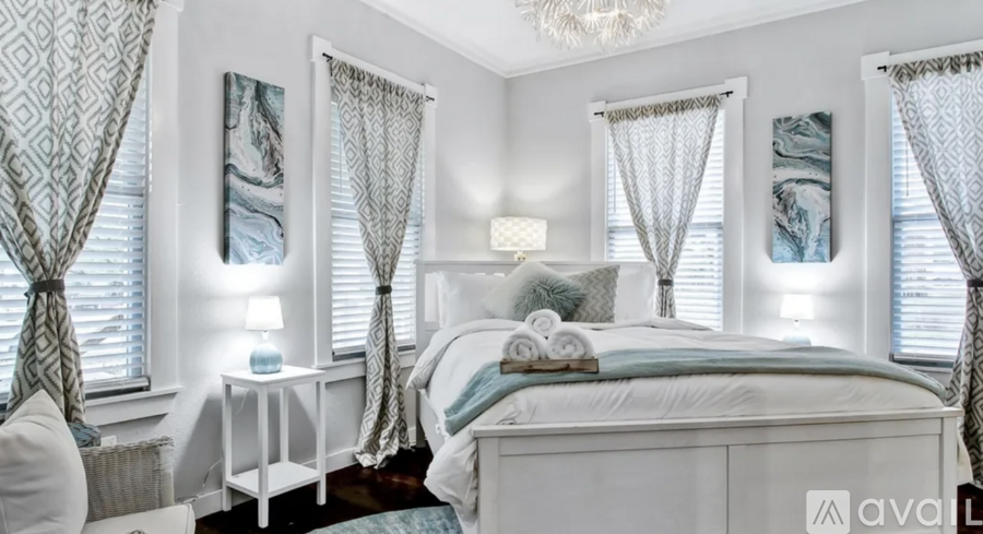 A bedroom with a large bed, a nightstand with a lamp, and a chandelier.