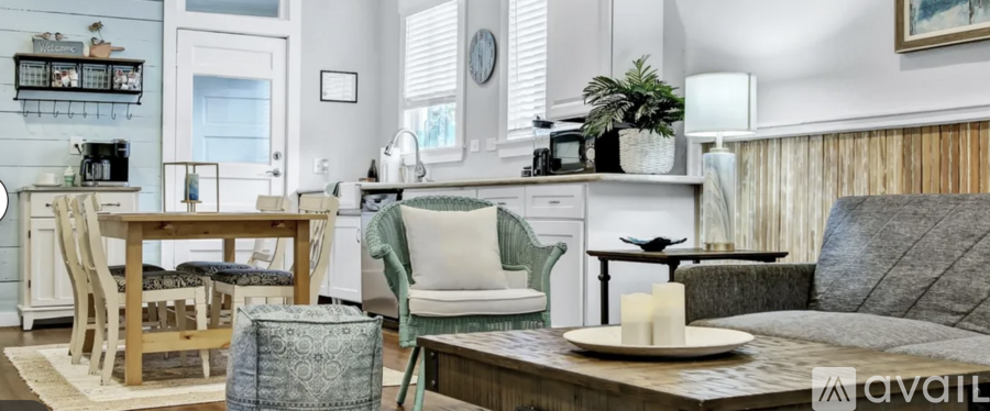 A living room with a grey couch, a wooden table, and a white chair.