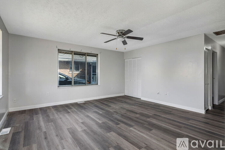 A room with a ceiling fan and a window with a view of a building outside.