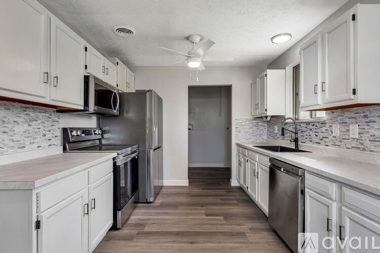 A kitchen with white cabinets and a marble backsplash.