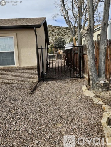 A black gate is on a brown fence.