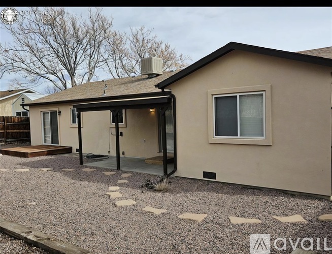 A house with a beige exterior and a gravel driveway.