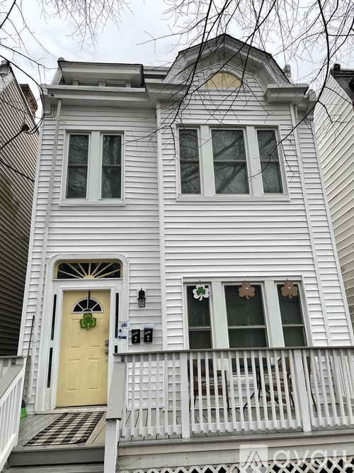A white house with a yellow door and a small porch.