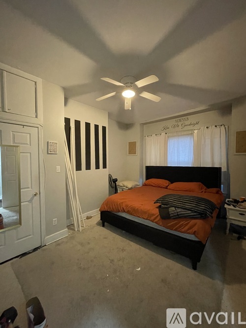 A bedroom with a bed, a ceiling fan, and a window with curtains.